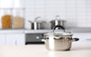 Casserole inox posées sur un comptoir de cuisine, avec deux poignées et un couvercle.
