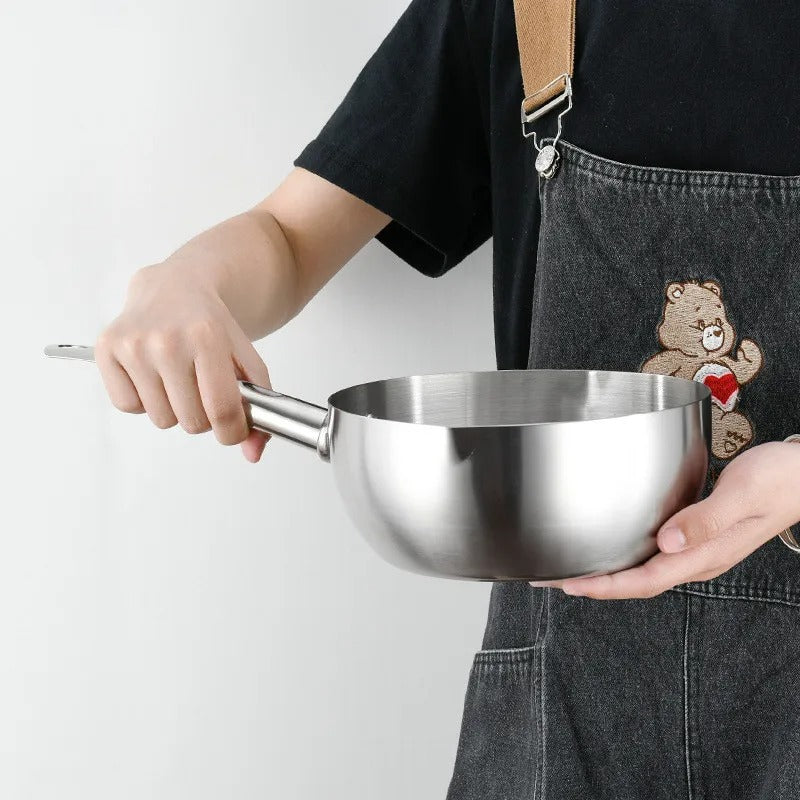 Casserole à Induction Polyvalente en Acier Inoxydable tenue dans les mains d'une femme qui porte un tablier