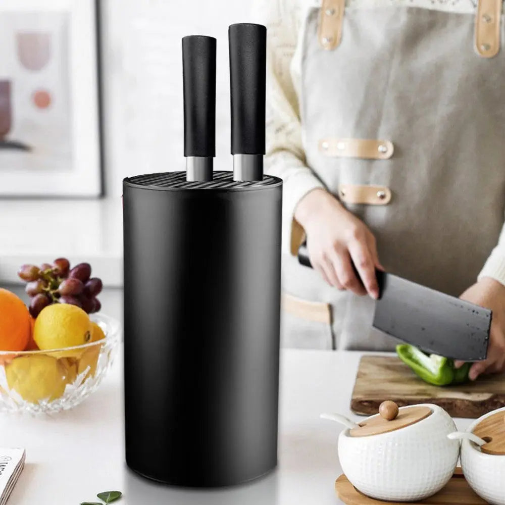 Porte Couteau Noir et Moderne sur une table avec des fruits àgauche et une personne coupant des légumes à droite